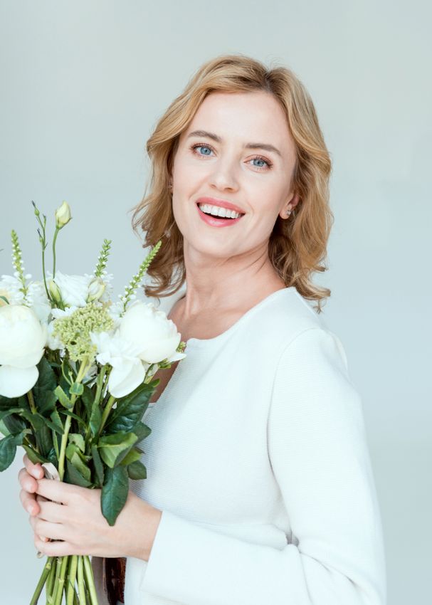 Smiling woman holding bouquet of white flowers.